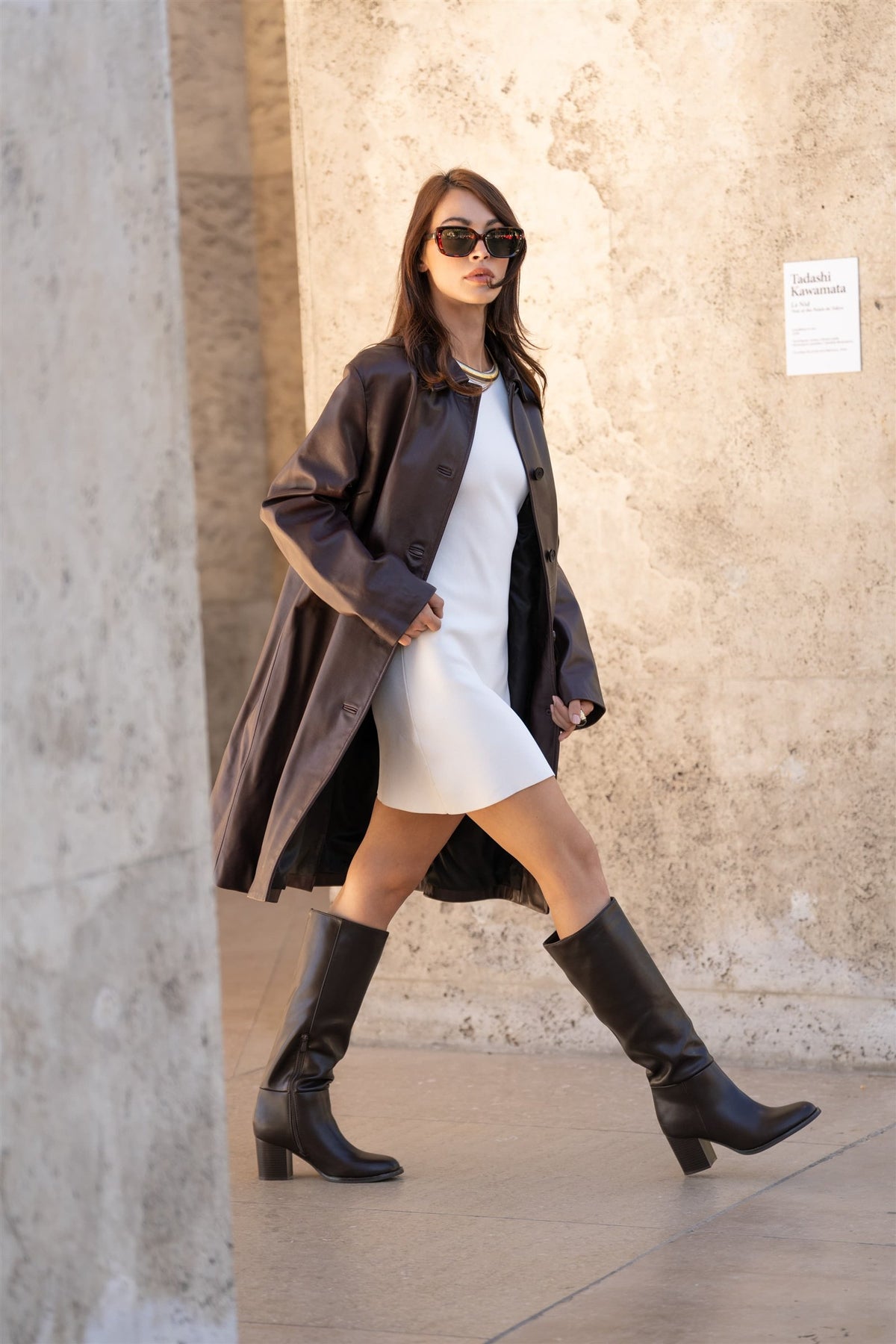 Une femme marche en manteau et bottes.